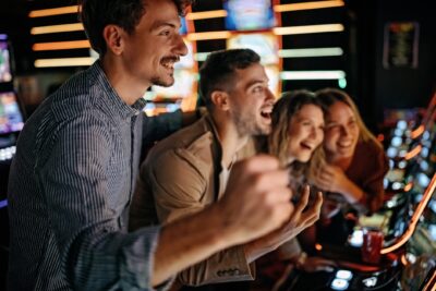 Group of friends cheering at casino slot machines.