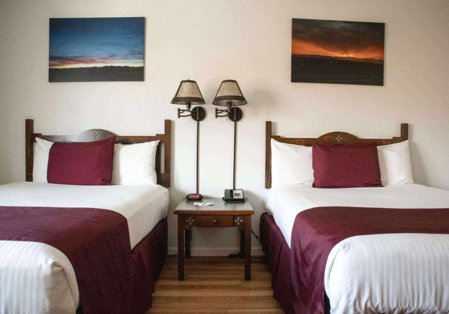 Two beds in a room with paintings on the wall.